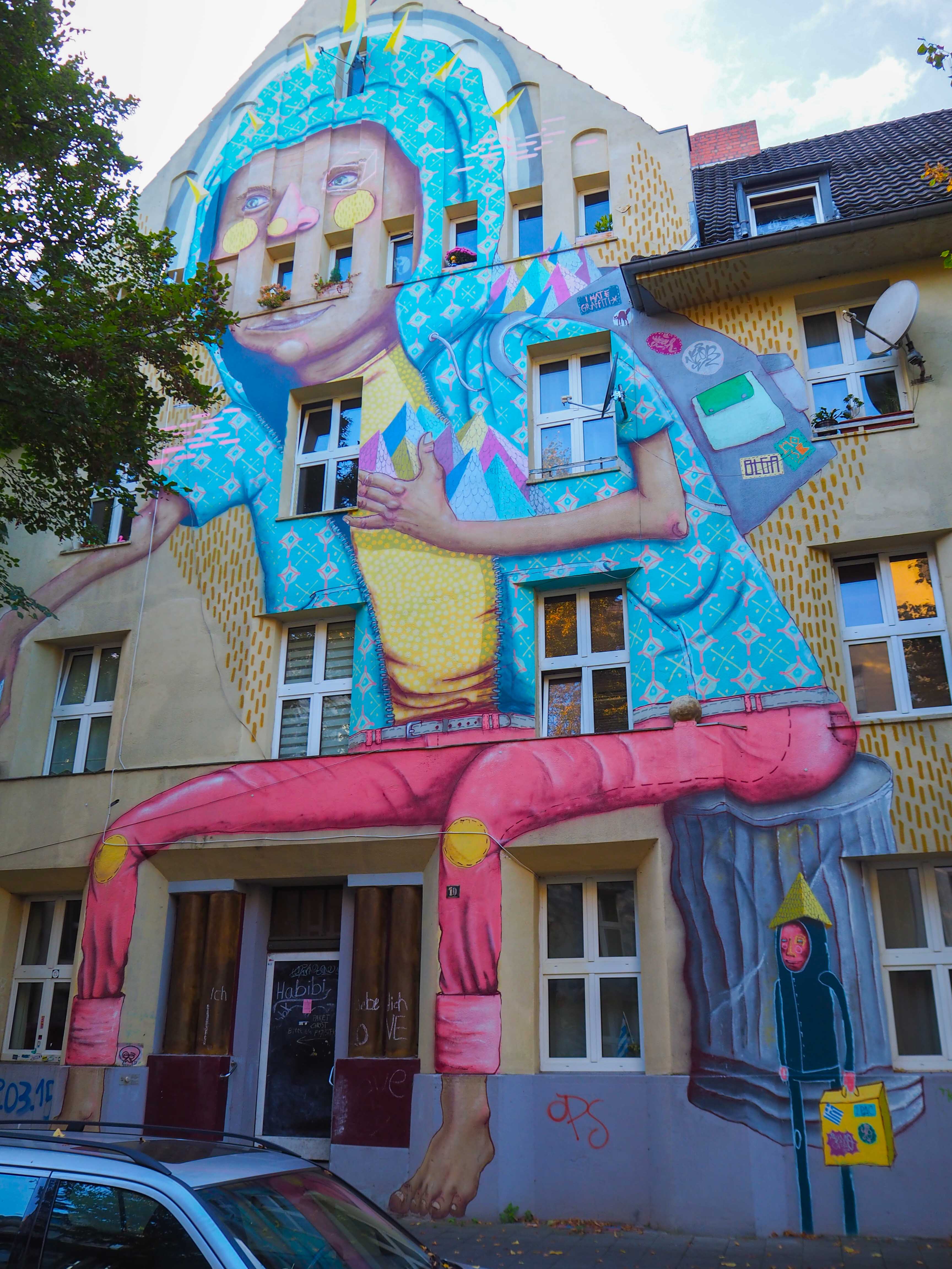 Os Gémeos hat eine überdimensional große Figur auf eine Hausfassade gemalt