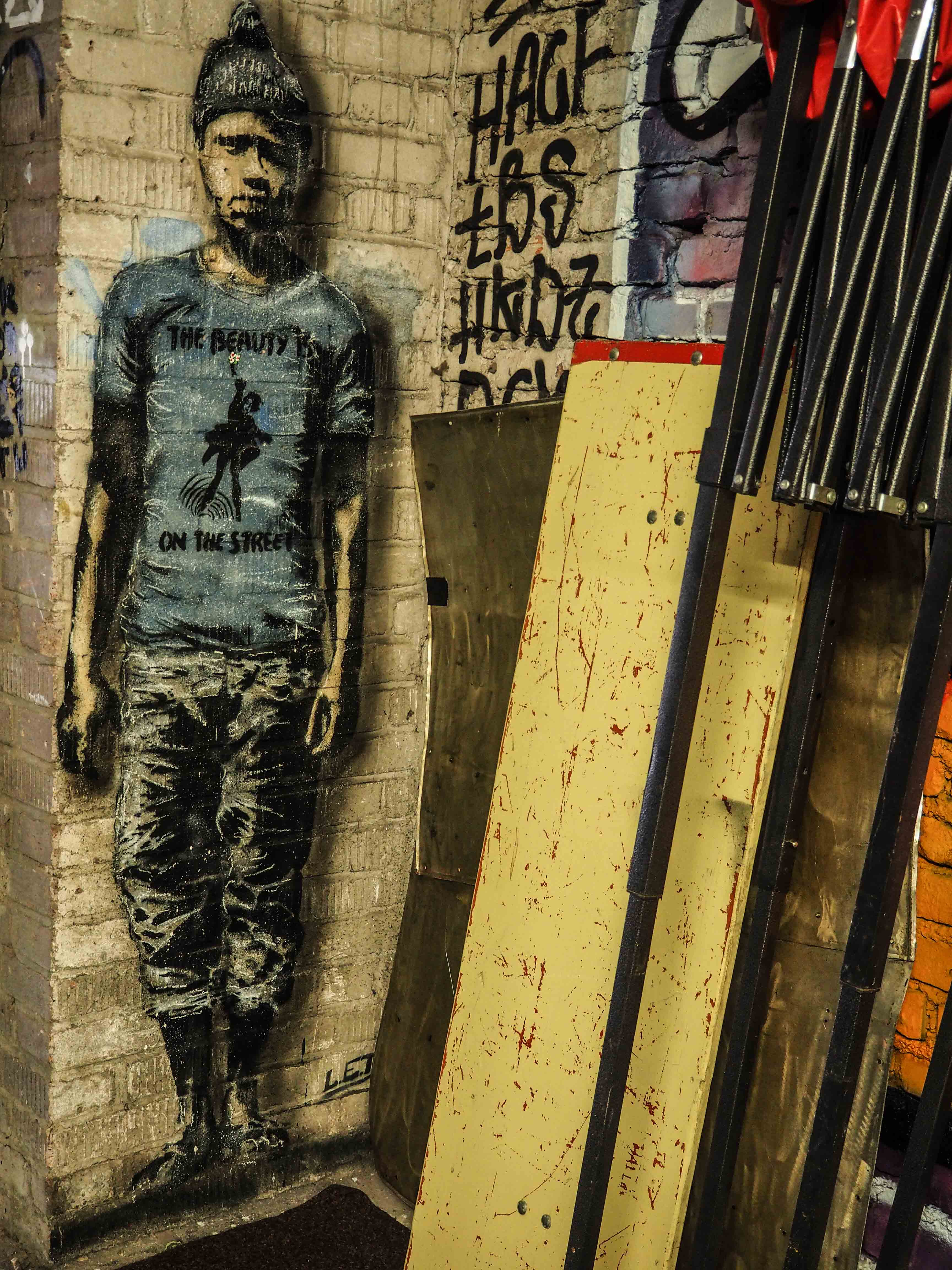 in der Ecke einer Halle steht hinter ein paar Brettern ein Junge, von LET gemalt