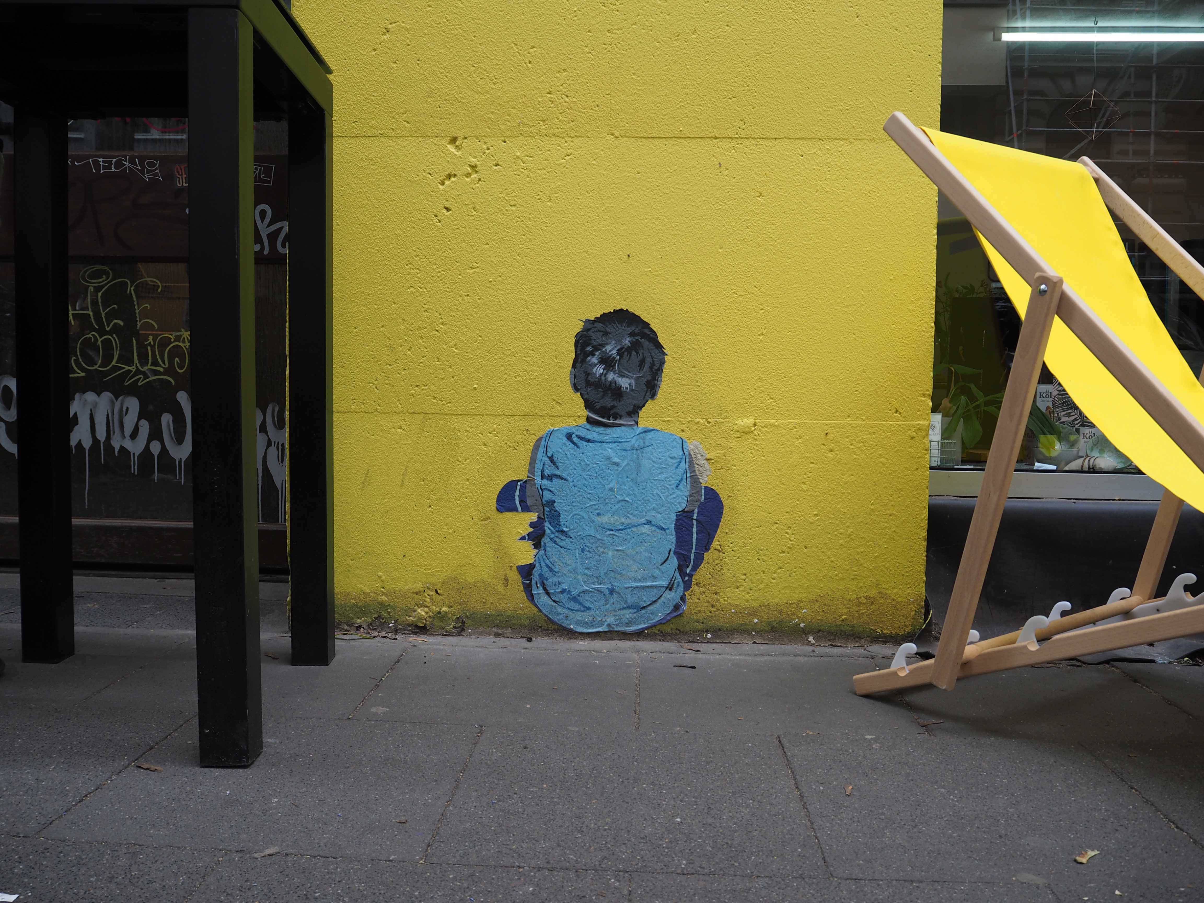 ein Junge sitzt von hinten dargestellt auf einer gelben Wand, Bild von Lei Leise