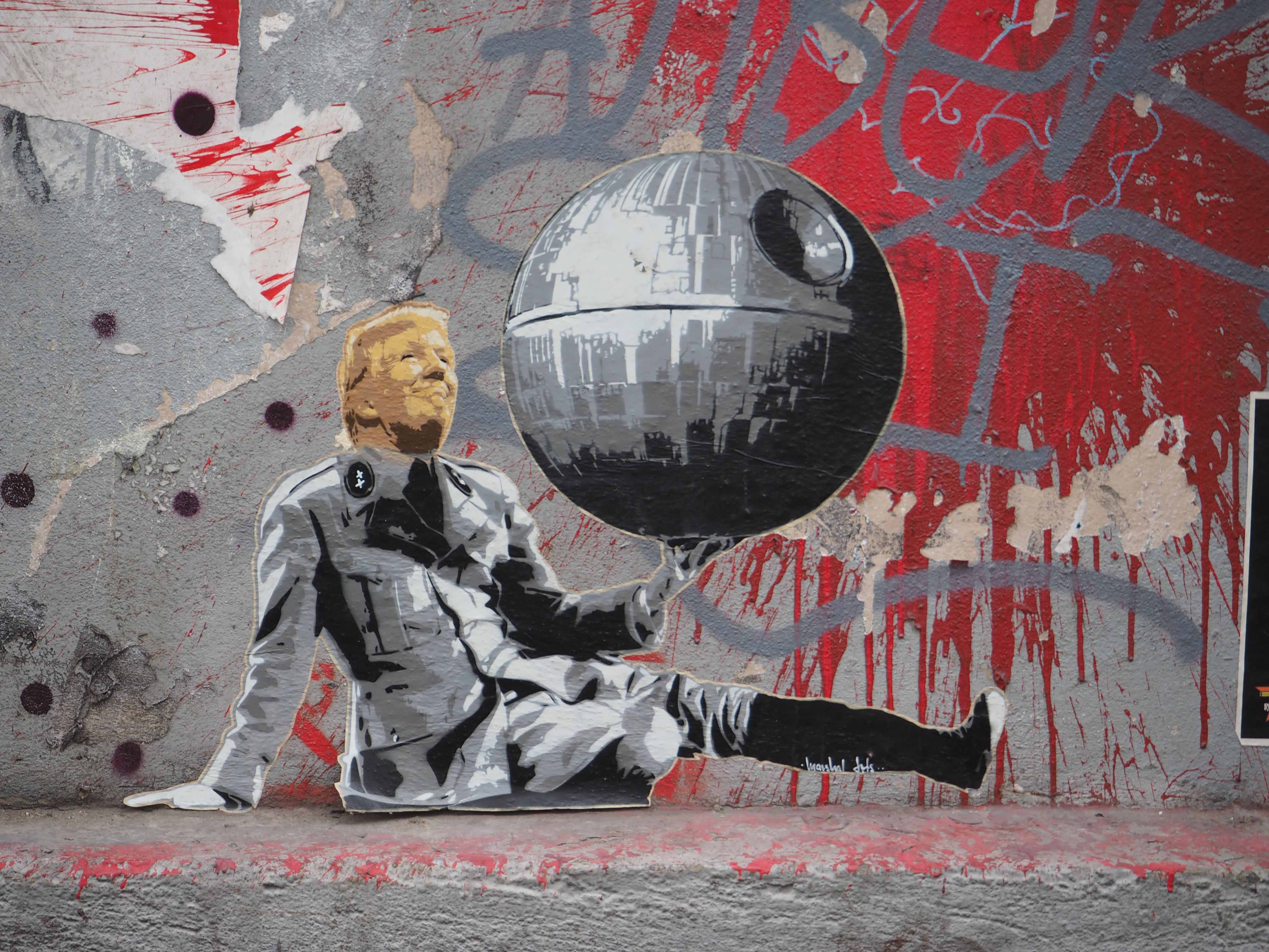 das Paste up von Marshal Arts zeigt D. Trump der wie im "Großen Diktator" mit der Weltkugel spielt