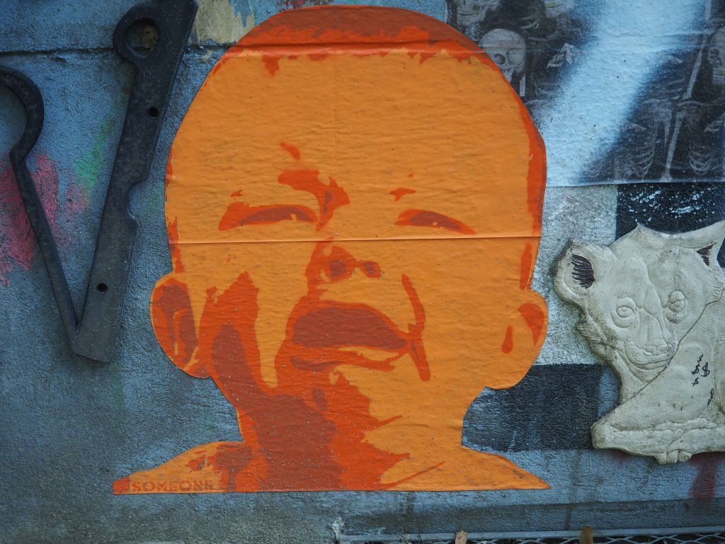 ein paste up von Someone das ein weinendes Baby in orange zeigt