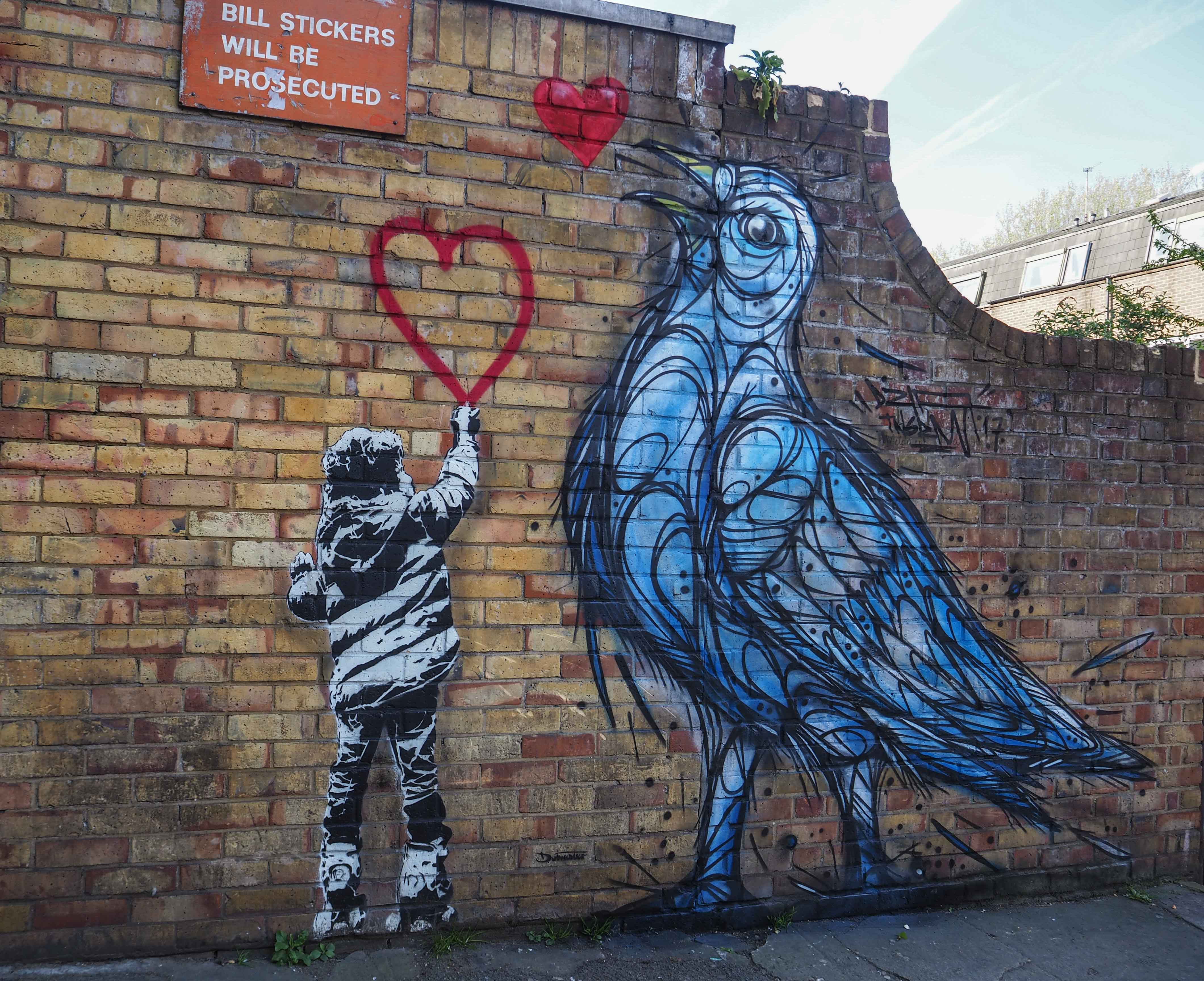 Mural von Dzia zeigt einen großen Vogel und einen Jungen der ein Herz malt