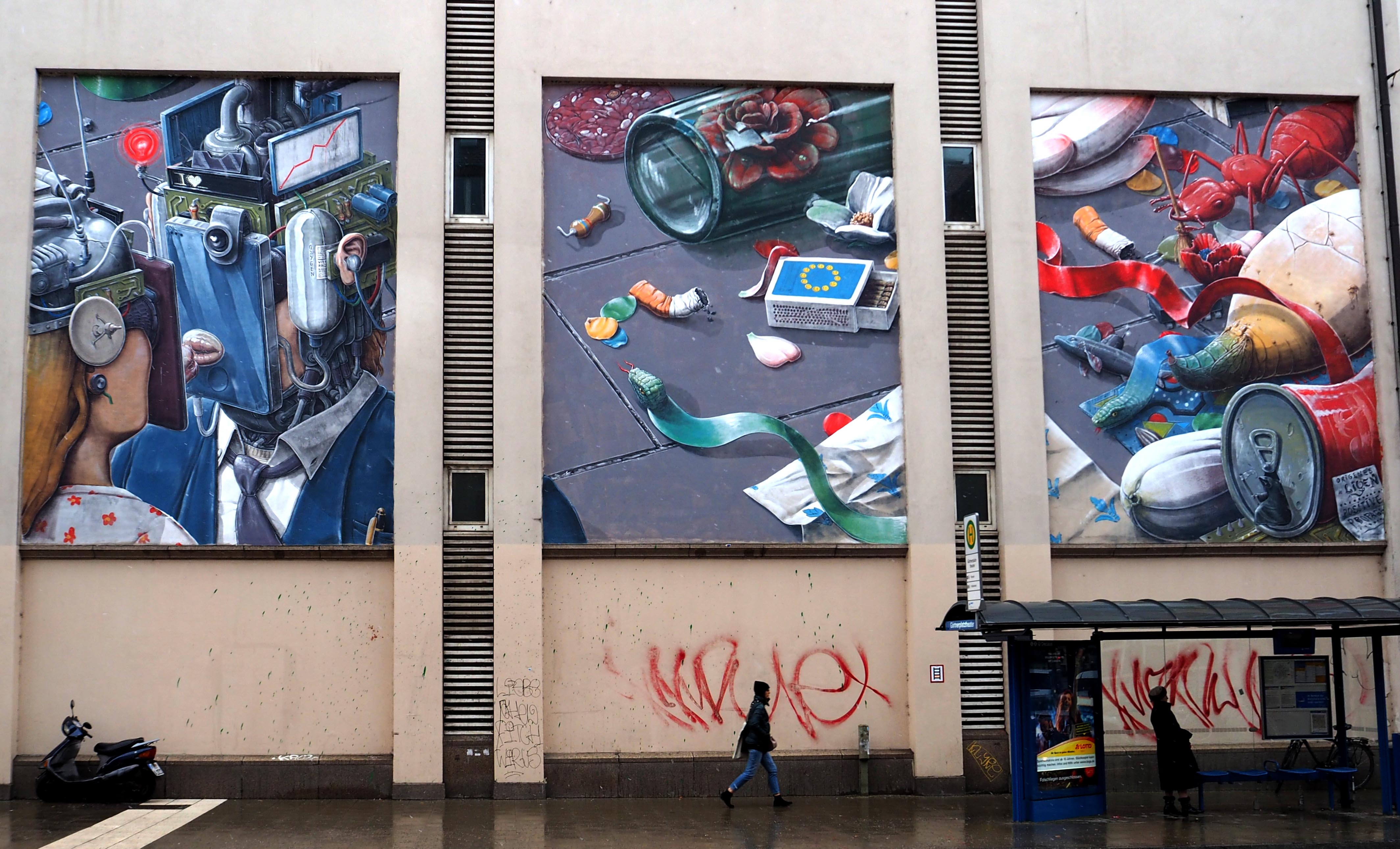 vor einer Bushaltestelle finden sich drei große Murals die die Dekadenz der Gesellschaft darstellen soll