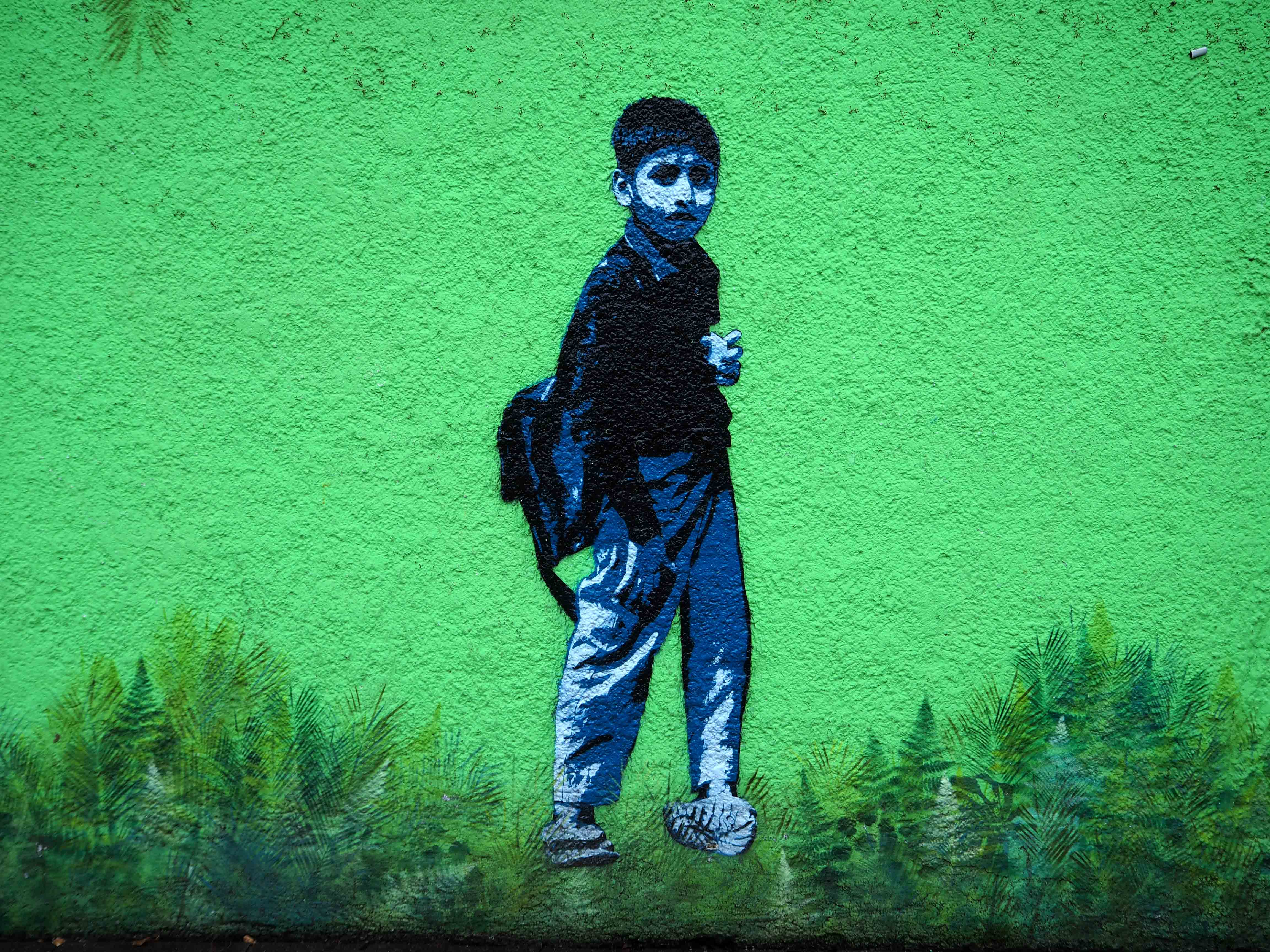 Stencil auf grüner Wand von Tona das einen Schuljungen darstellt