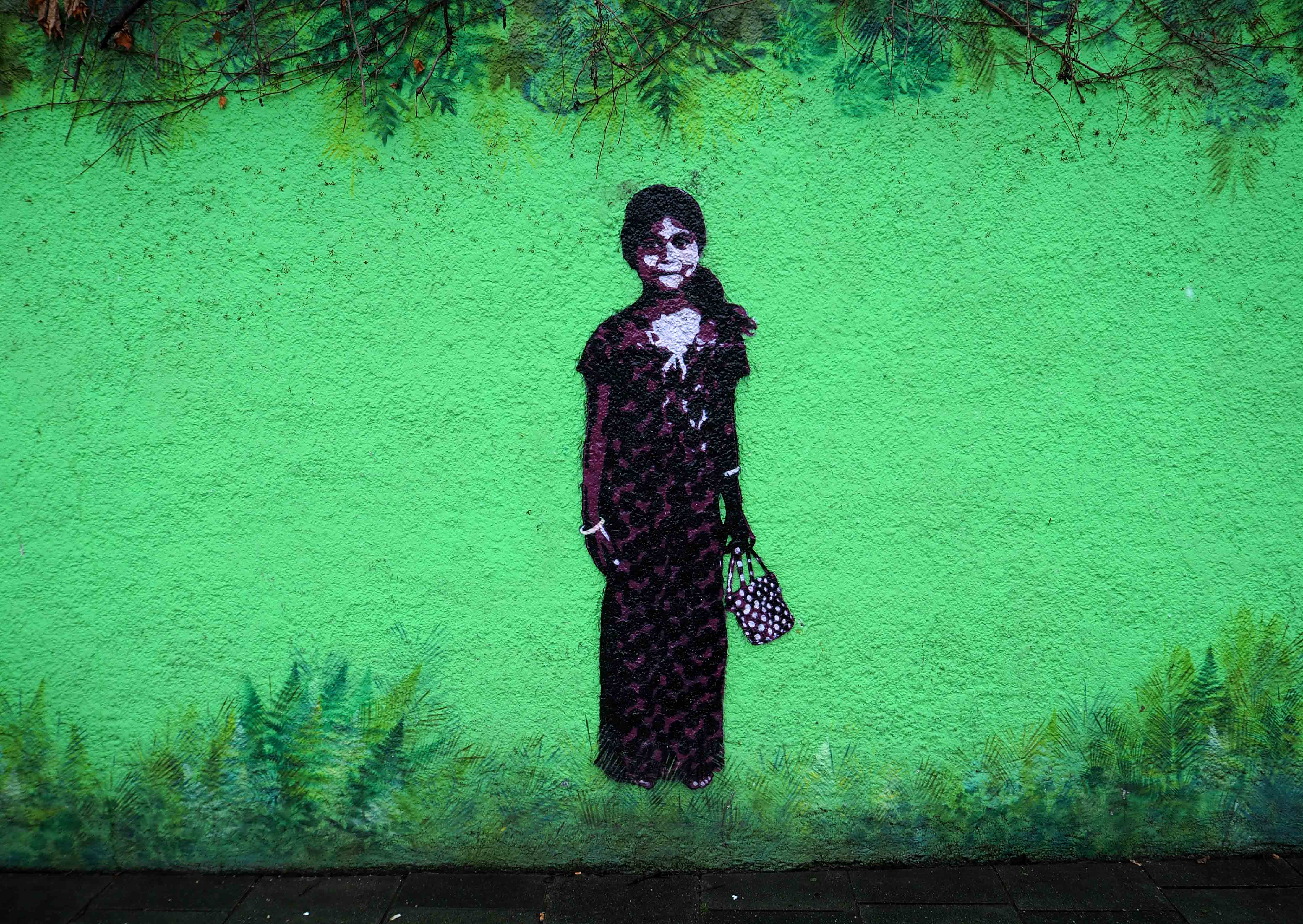 ein junges Mädchen von Tona als Stencil auf einer grüngestalteten Wand