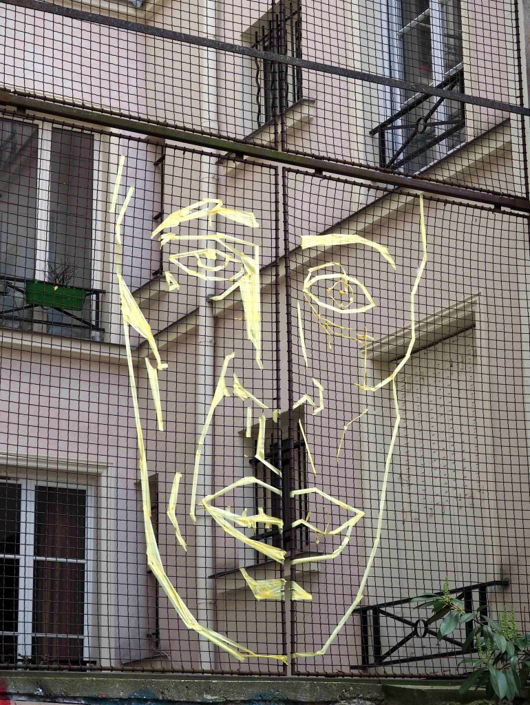 mit Tesakrepp geklebtes Gesicht auf einem Gitter