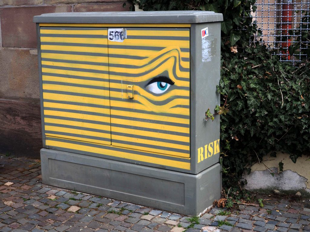 Stromkasten aus dem ein Auge durch gelbe Linien sieht