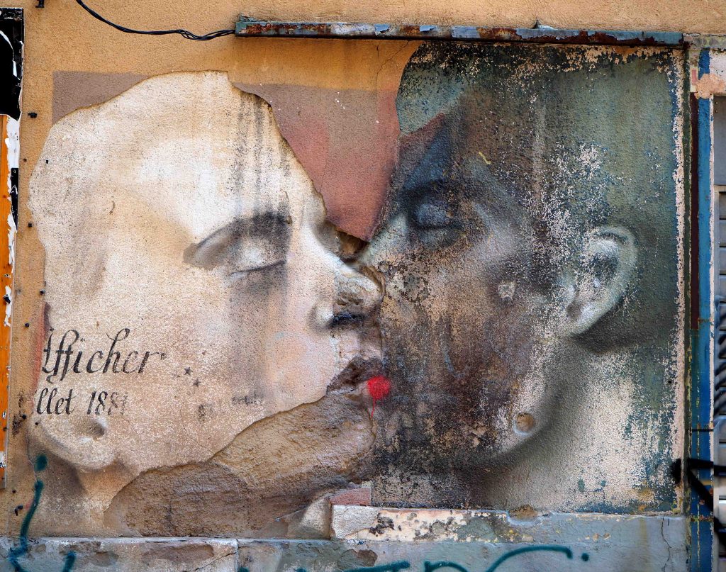 sich küssende Menschen an verfallener Mauer